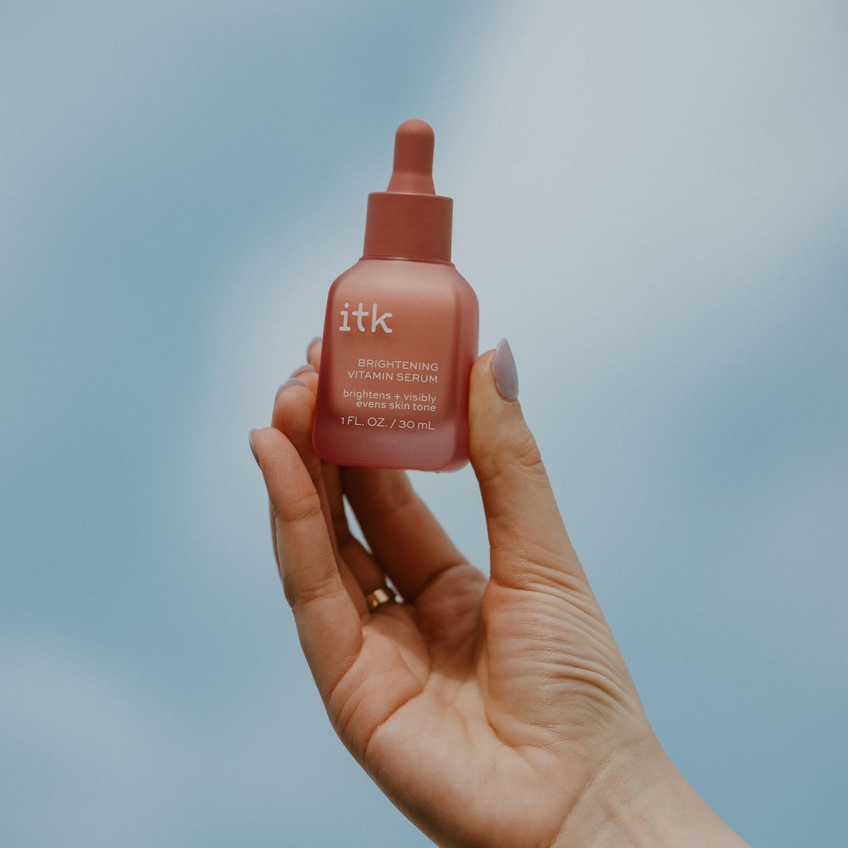 ITK serum in hand scale to illustrate one-ounce size and travel-friendly benefit