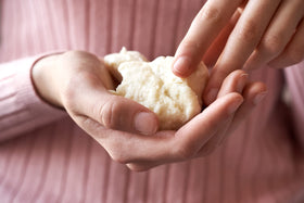 Jersey Botanical hand scooping shea butter demonstrating easy application and controlled use benefit