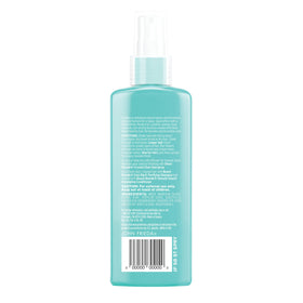 John Frieda bottle in hand to show scale and travel-friendly 5 ounce size