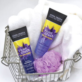 Hands holding John Frieda bottles next to ruler for scale showing travel-friendly 8.3 oz size