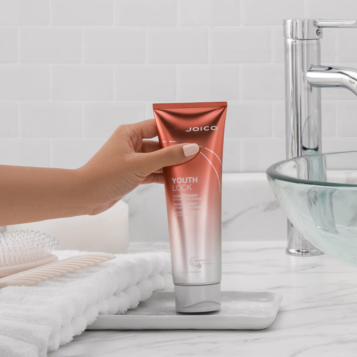 Joico YouthLock conditioner held in hand to show 8.5 fl oz size and scale
