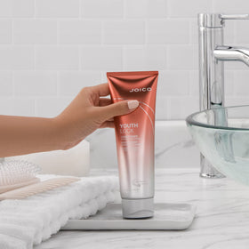 Joico YouthLock conditioner held in hand to show 8.5 fl oz size and scale