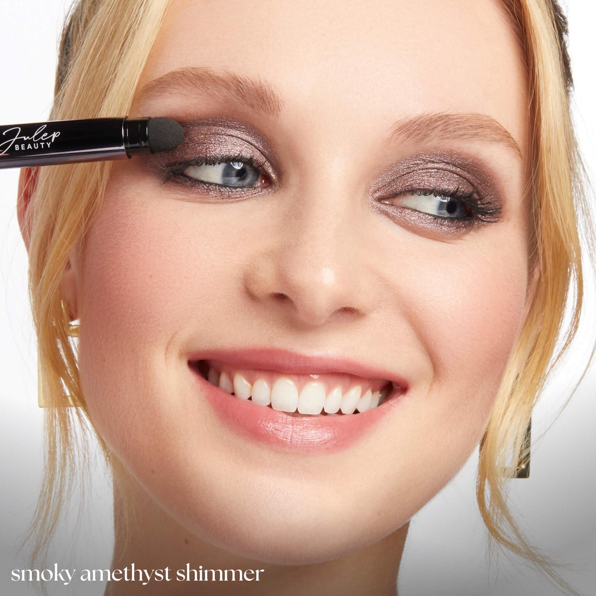 model applying Julep Smoky Amethyst across full eyelid for one-step shimmer look