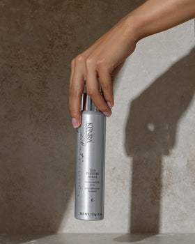 Kenra bottle held in hand to show size and travel-ready benefit