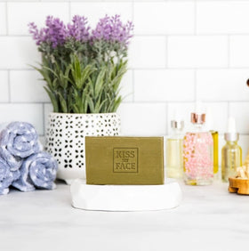 Kiss My Face soap beside dish to show compact size and travel-friendly benefit