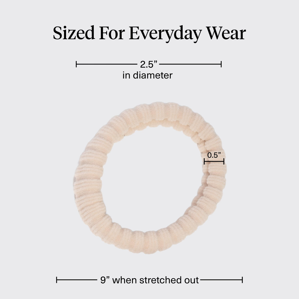 Kitsch hair tie beside a hand for scale and to illustrate compact, travel-friendly size