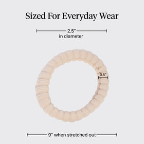 Kitsch hair tie beside a hand for scale and to illustrate compact, travel-friendly size