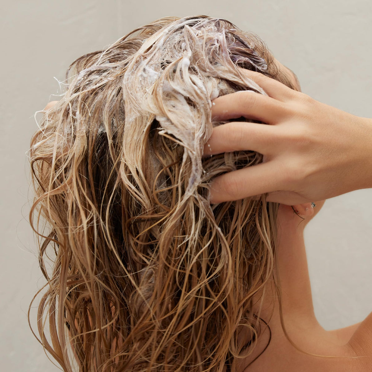 Kristin Ess before and after hair strand showing reduced brass and shine