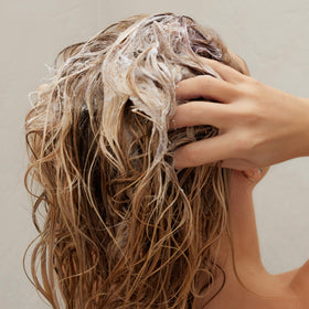 Kristin Ess before and after hair strand showing reduced brass and shine