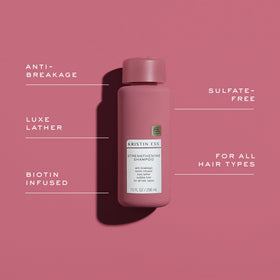 Hand holding Kristin Ess shampoo to show bottle size and easy use benefit