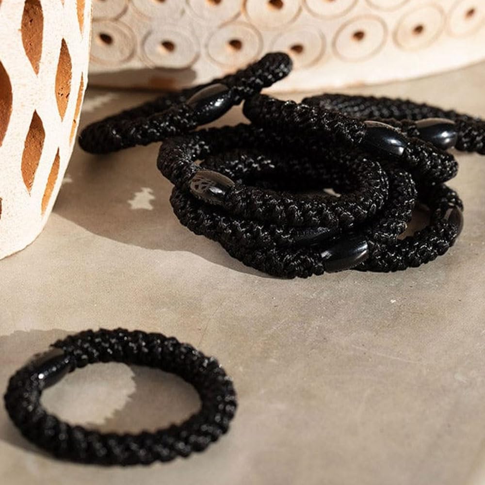 Eight L. Erickson black hair ties arranged flatlay showing uniformity and wardrobe-ready set benefit