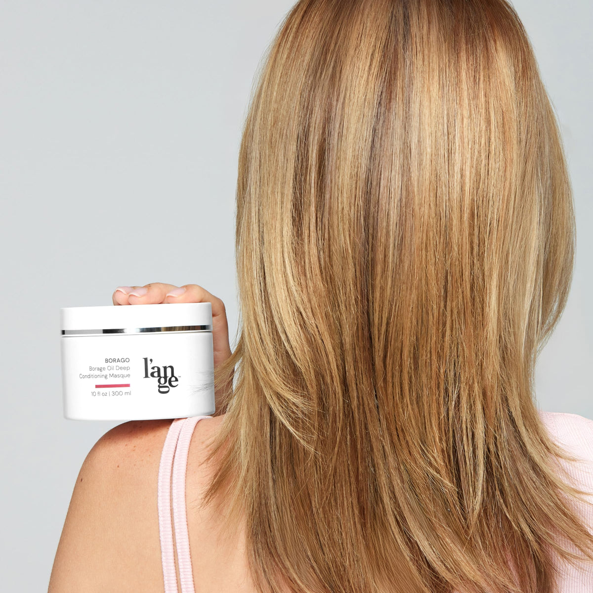 L'ANGE HAIR jar next to hand showing 10 oz size and scale benefit