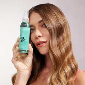 L'ANGE HAIR 4 oz bottle beside smartphone for compact, on-the-go convenience