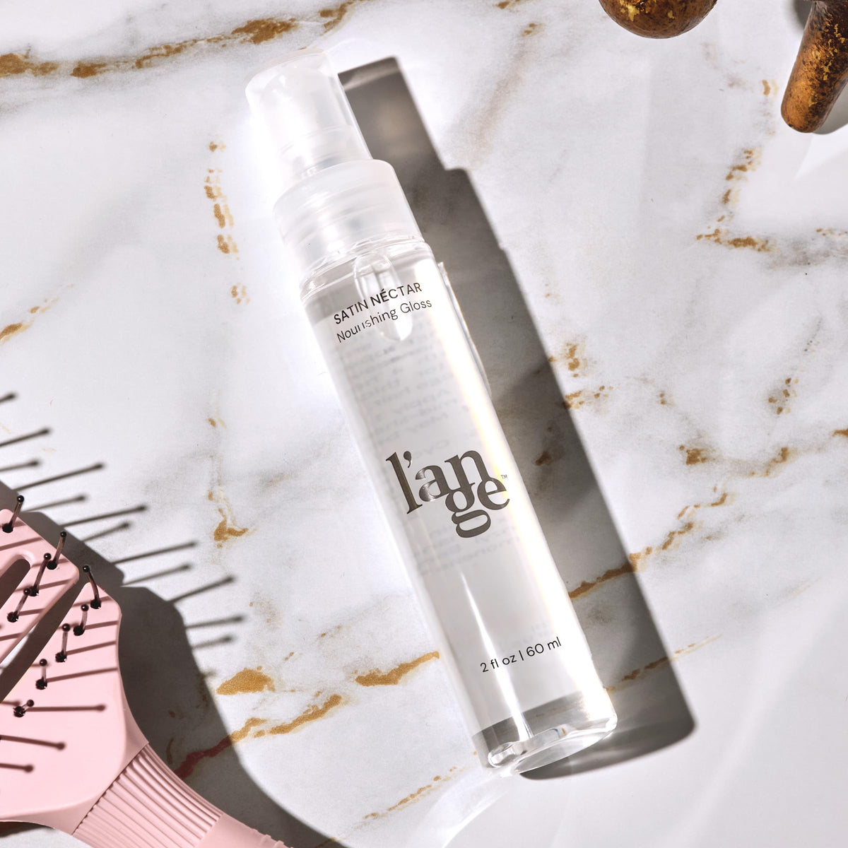 L'ANGE HAIR bottle next to passport illustrating travel-ready convenience