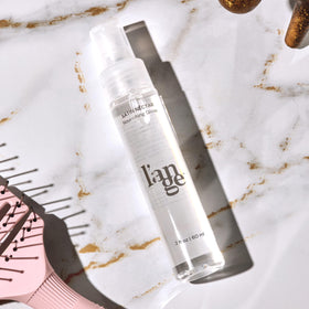 L'ANGE HAIR bottle next to passport illustrating travel-ready convenience