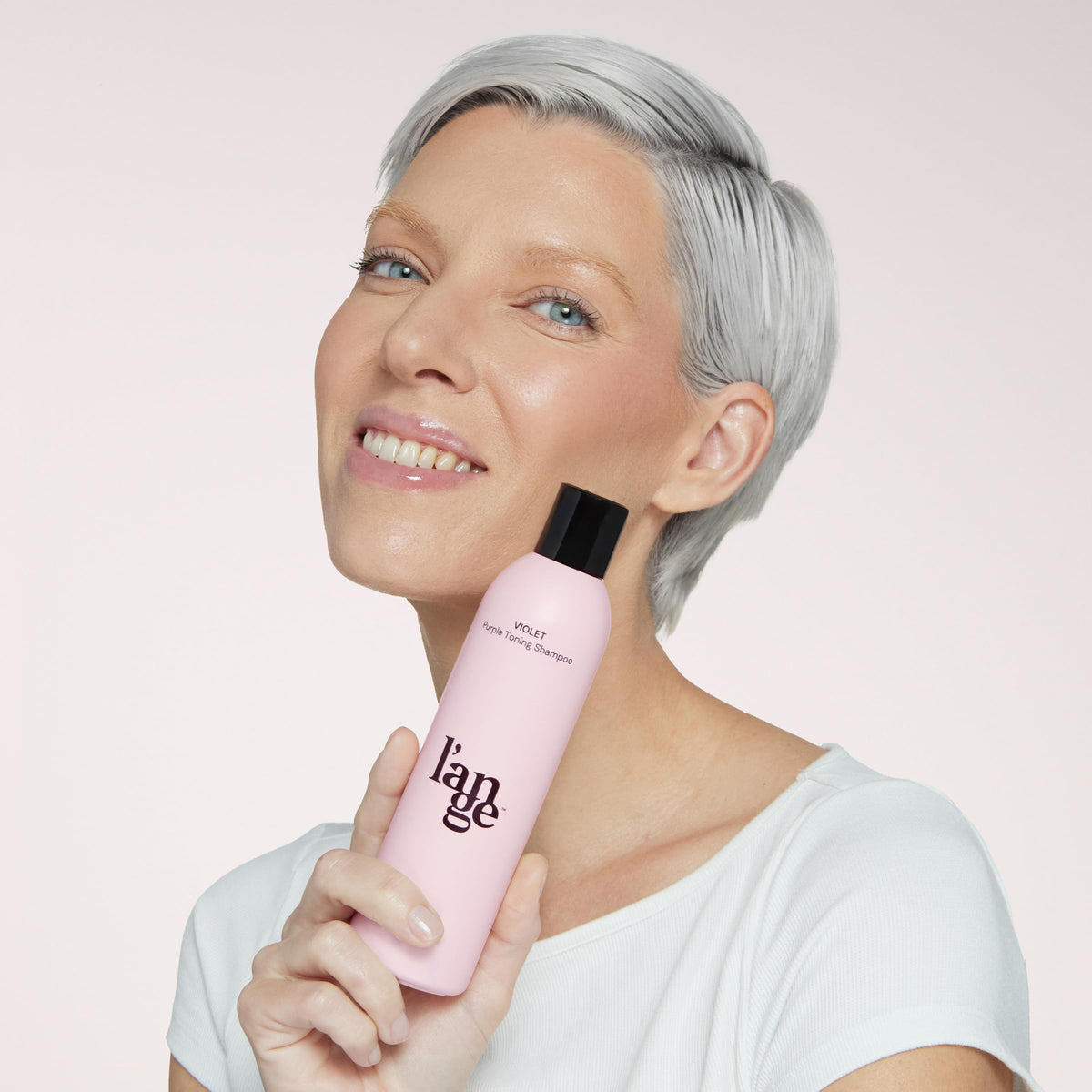 L'ANGE HAIR bottle held in hand to show actual size and travel-friendly benefit