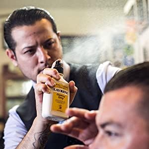 Layrite grooming spray in hand showing 6.7 oz scale and travel-friendly benefit
