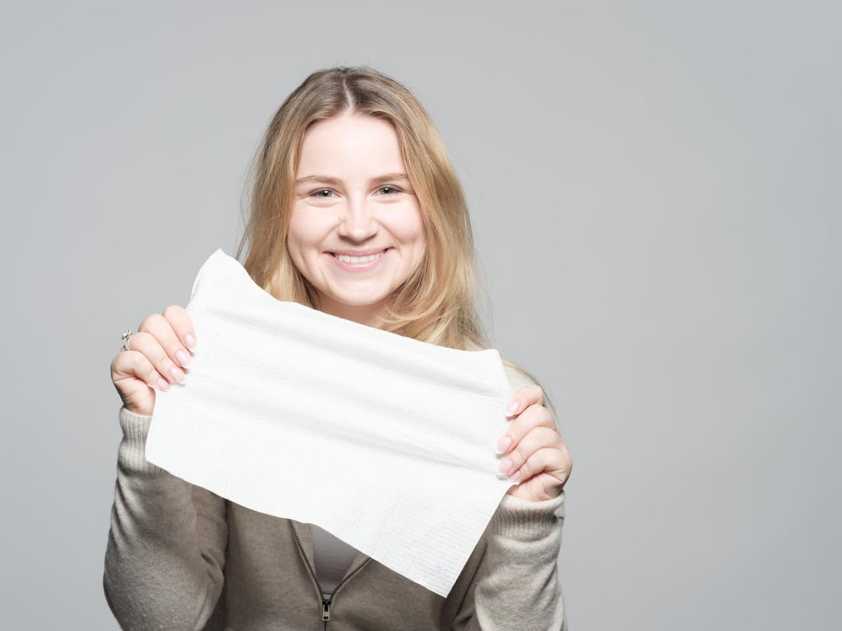 Le Visage towel next to a hand illustrating size and coverage benefit