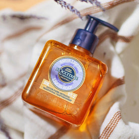L'OCCITANE bottle next to a hand demonstrating 10.10 fl. oz size and usability