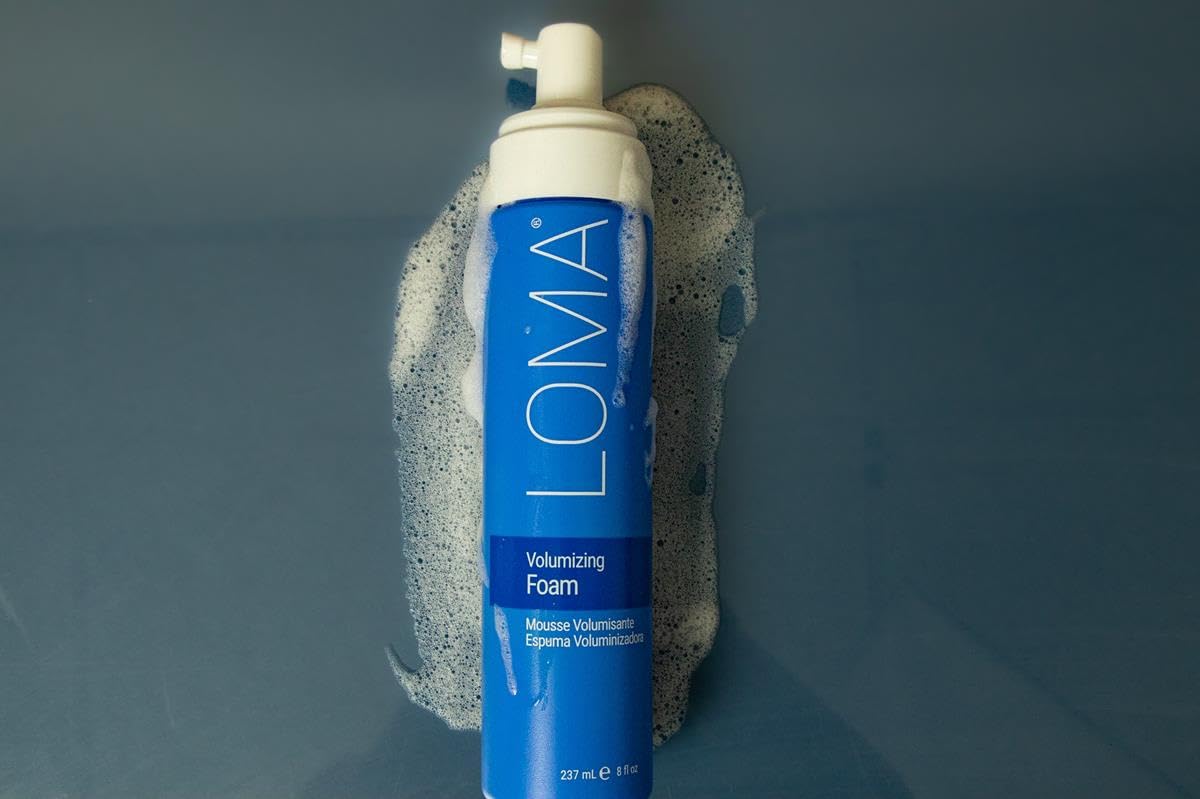 LOMA foam size comparison with hand showing 8.45 oz bottle for scale and travel suitability