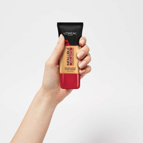 L'Oreal Paris bottle in hand to show 1 fl oz scale and portable convenience benefit