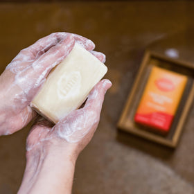 Hand holding Lume soap with rich lather showing gentle, effective cleansing