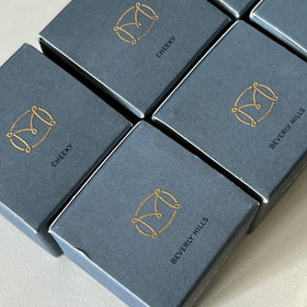 M Flush Balm next to hand for size comparison showing travel-ready compact benefit portability