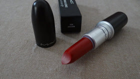 MAC lipstick next to hand to show scale and travel-friendly 0.1 oz size