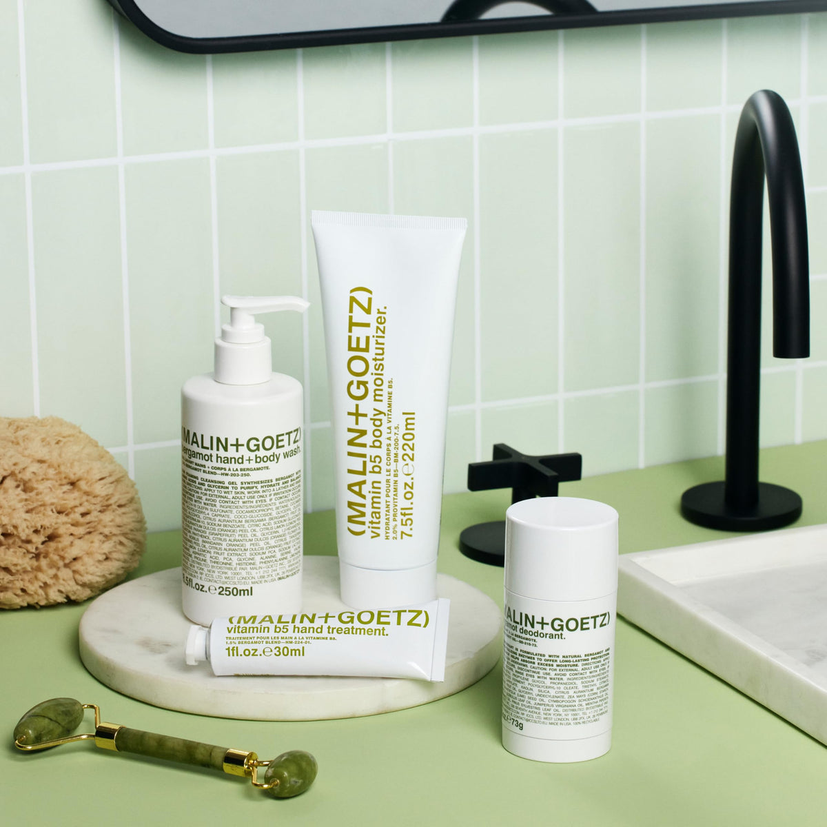MALIN+GOETZ bottle held for scale conveying compact travel-friendly benefit