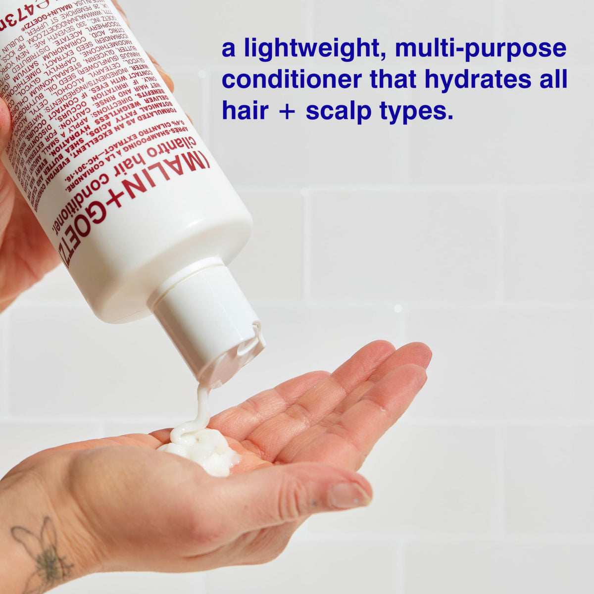 MALIN+GOETZ conditioner being applied in shower demonstrating frizz control benefit