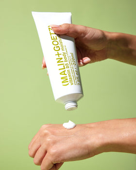 MALIN+GOETZ label close-up featuring ingredient highlights like provitamin B5 and shea butter