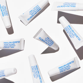 MALIN+GOETZ in a travel bag lifestyle shot emphasizing on-the-go moisture care