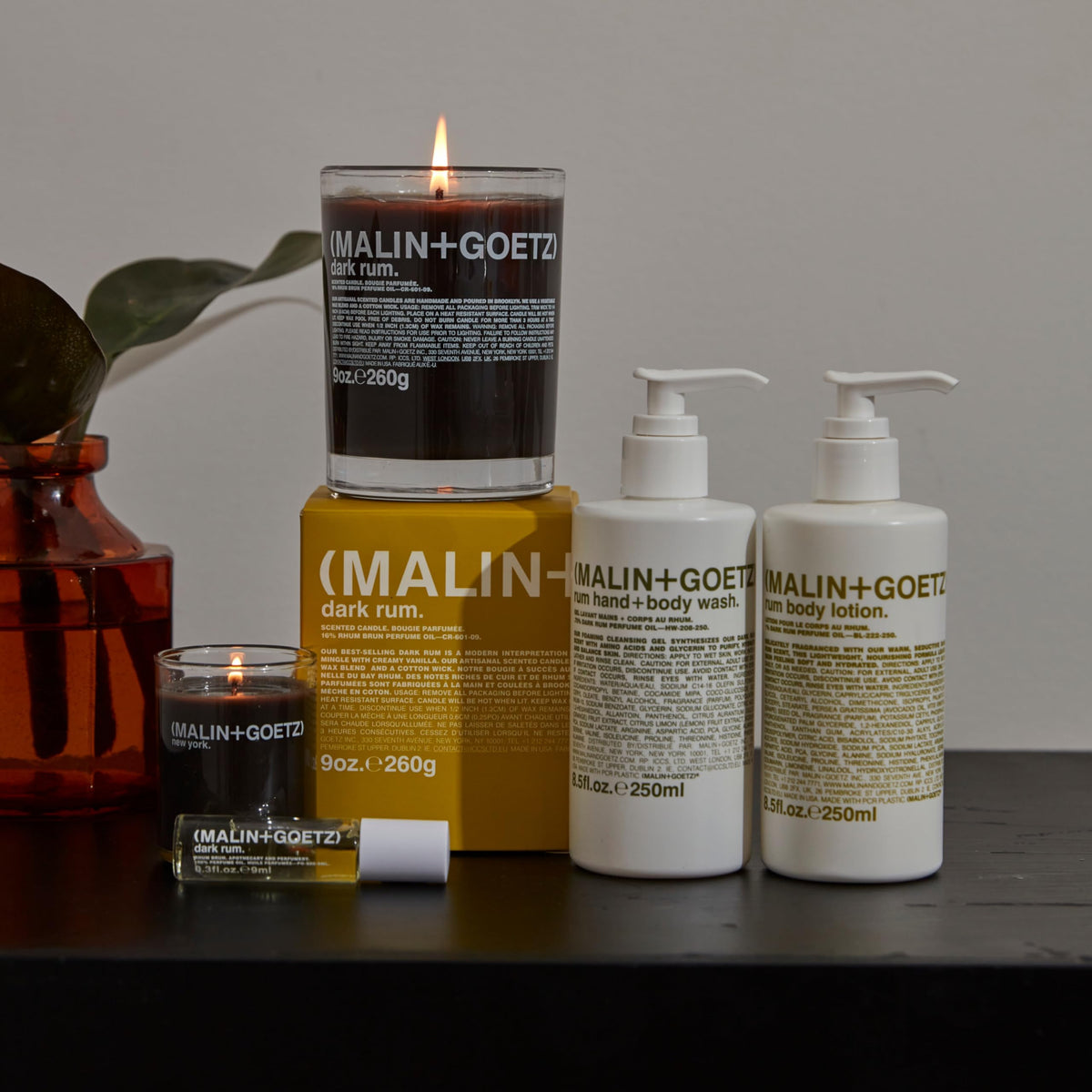 MALIN+GOETZ bottle next to hand showing 8.5 fl oz scale and travel-friendly size