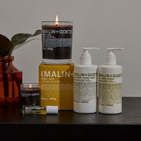 MALIN+GOETZ bottle next to hand showing 8.5 fl oz scale and travel-friendly size