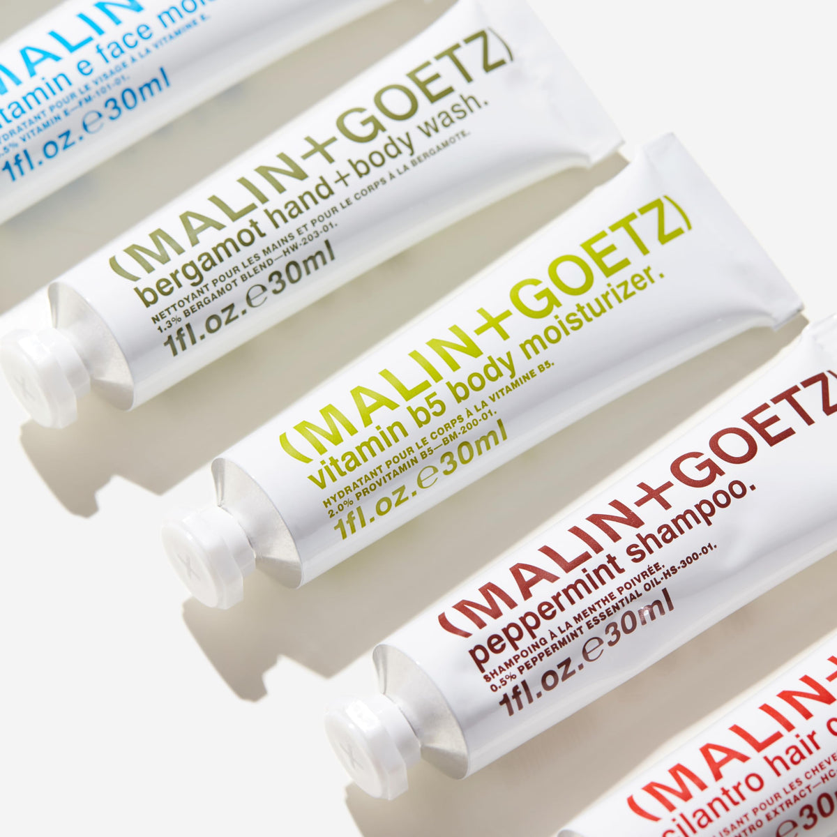 MALIN+GOETZ kit next to passport and boarding pass showing TSA-friendly sizes benefit