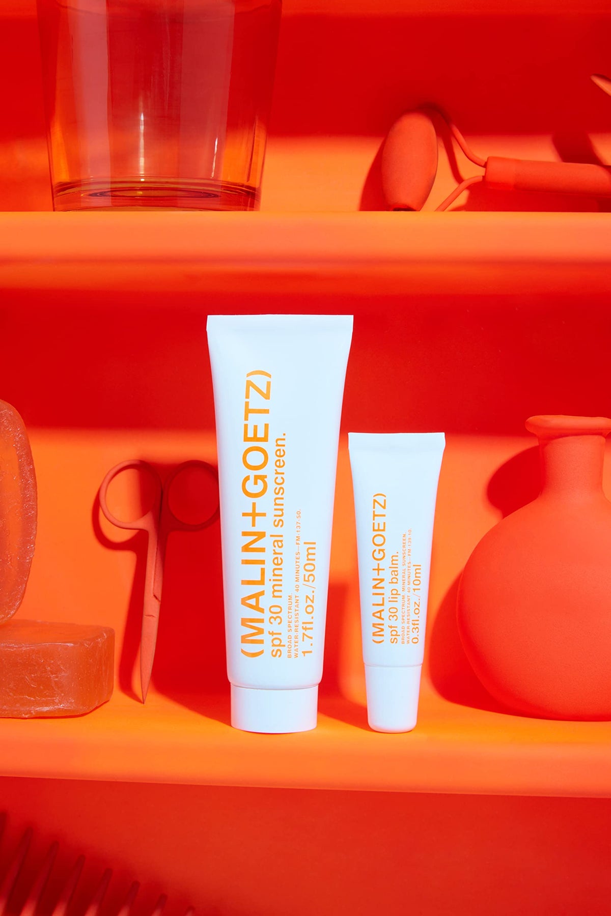 MALIN+GOETZ lip balm applied on lips outdoors, refreshing spearmint cooling benefit