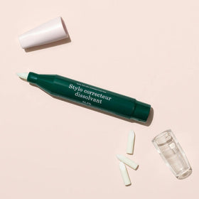 Manucurist corrector pen scale next to fingers illustrating travel-friendly compact size