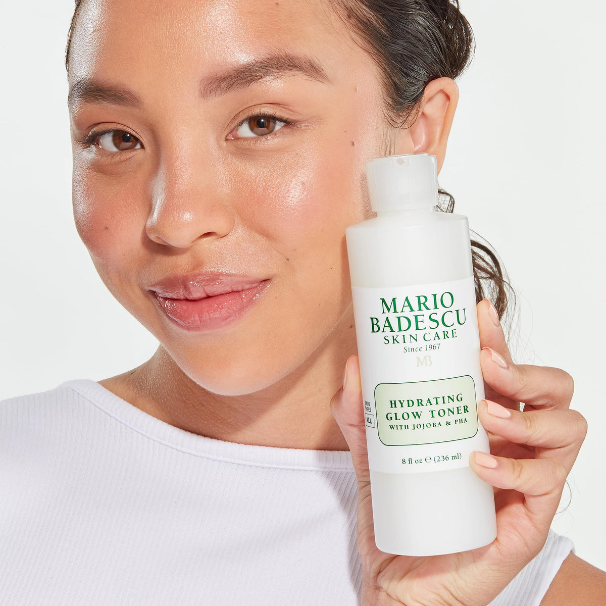 Mario Badescu bottle next to a moisturizer to show travel-friendly size comparison