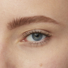 Maybelline Brow Tattoo next to a coin to show 4.9 ml compact size for travel ease