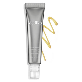 Medik8 eye cream next to coin for scale illustrating compact 0.5 oz travel-friendly size