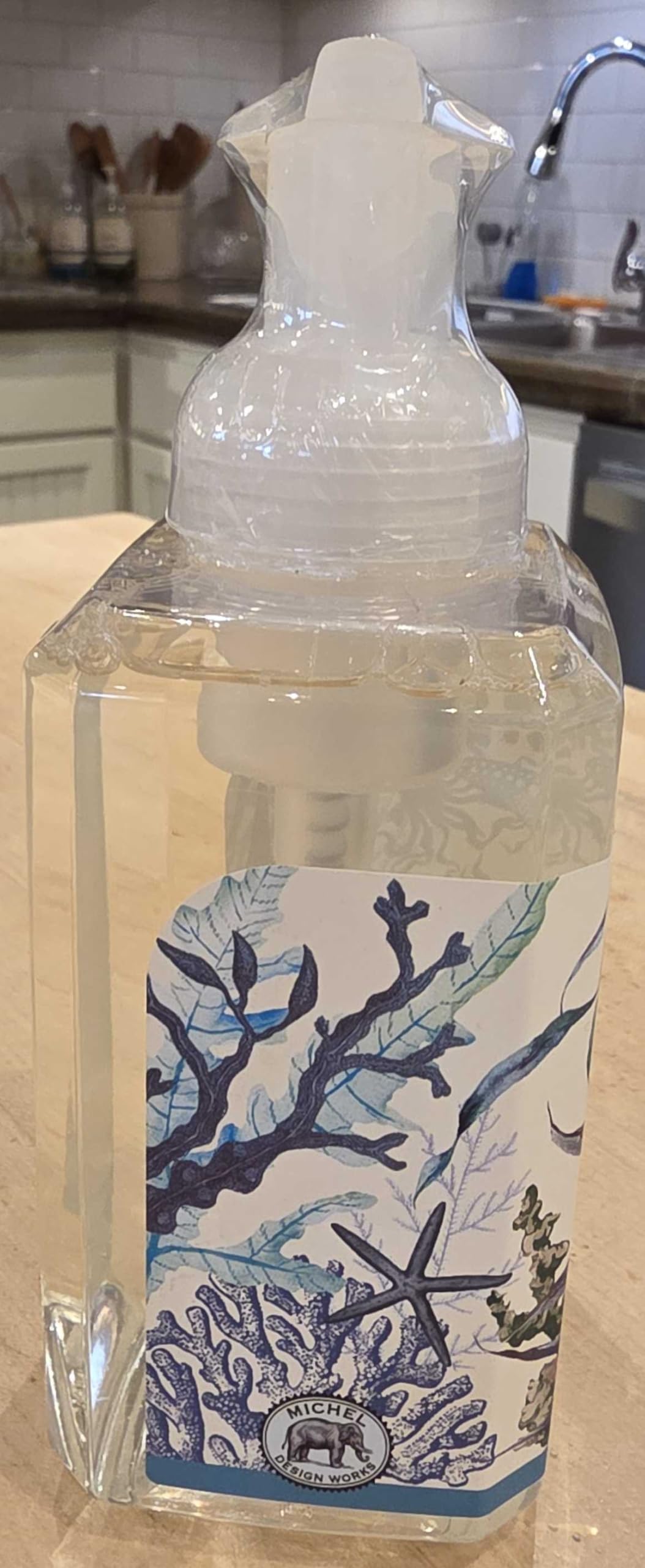 Michel Design Works bottle held by hand to show size and convenient countertop scale