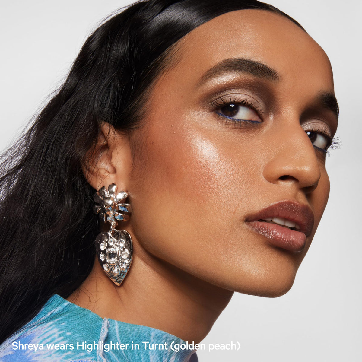 Milk Makeup highlighter on vanity beside brushes for styling and everyday routine
