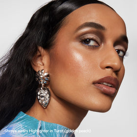 Milk Makeup highlighter on vanity beside brushes for styling and everyday routine