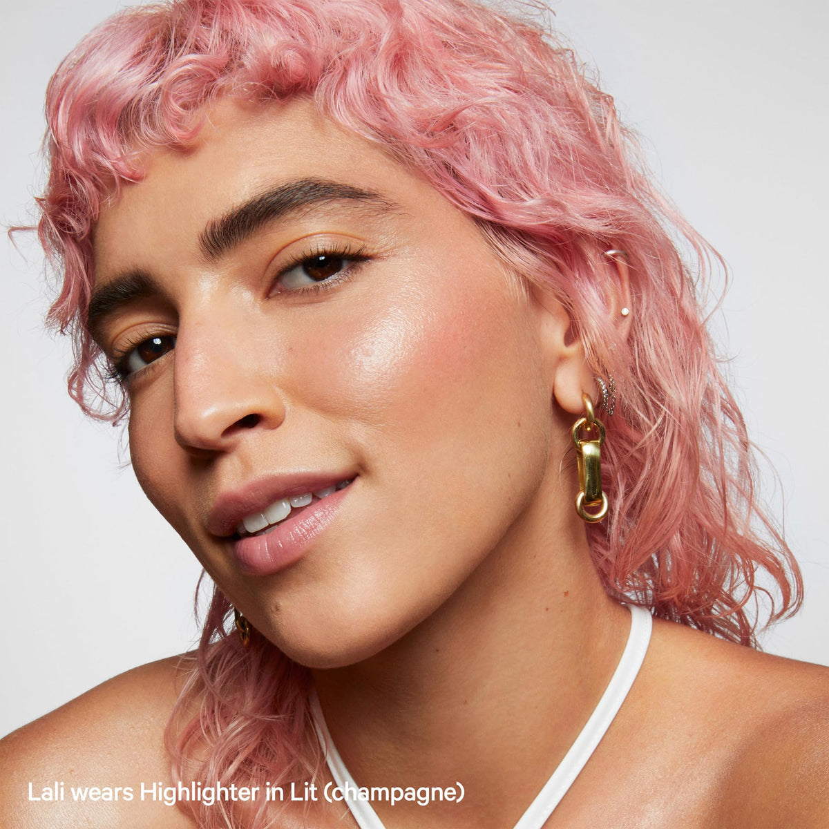 Milk Makeup Lit swiped on collarbones and shoulder, delivering all-over shimmer