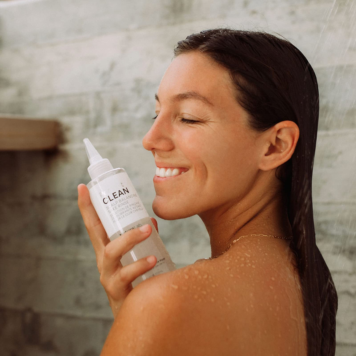 NATURELAB. TOKYO bottle in a bathroom setting implying spa-like scalp treatment ritual