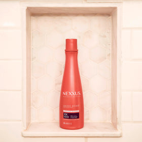 Nexxus conditioner held in hand to show 13.5 oz size and portability benefit