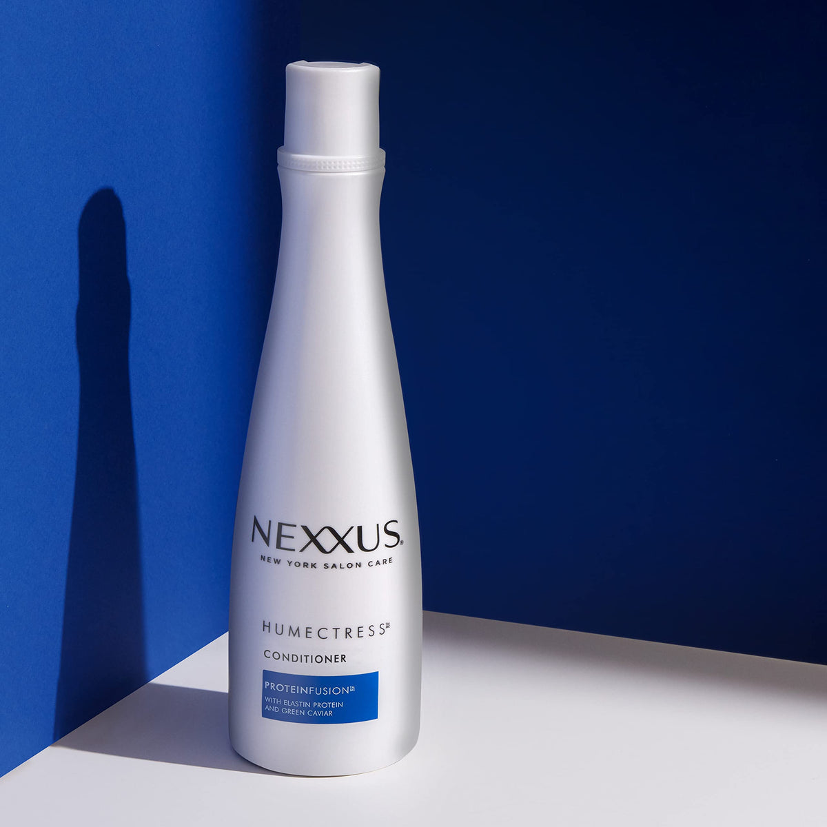 Nexxus bottles in hand indicating 13.5 oz size and travel-friendly benefit