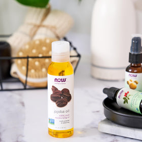 NOW Foods jojoba oil used on elbows in lifestyle shot showing conditioning benefit