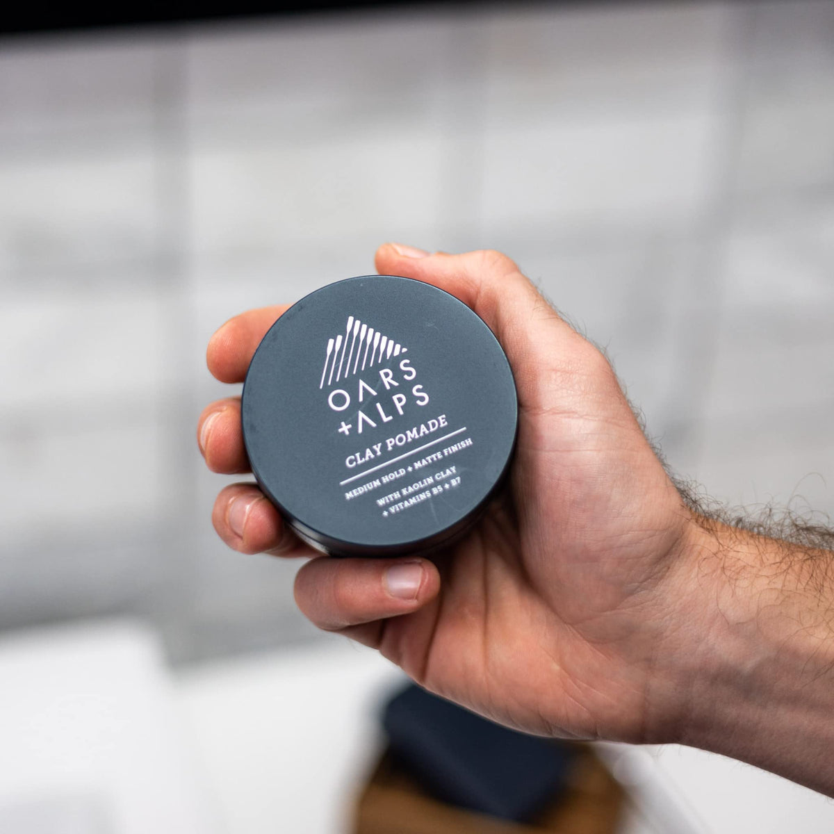 Oars + Alps jar in hand illustrating compact 2oz travel-friendly size