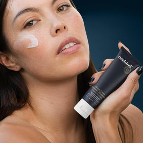 Onekind cream being applied to cheek illustrating smooth finish and improved skin texture